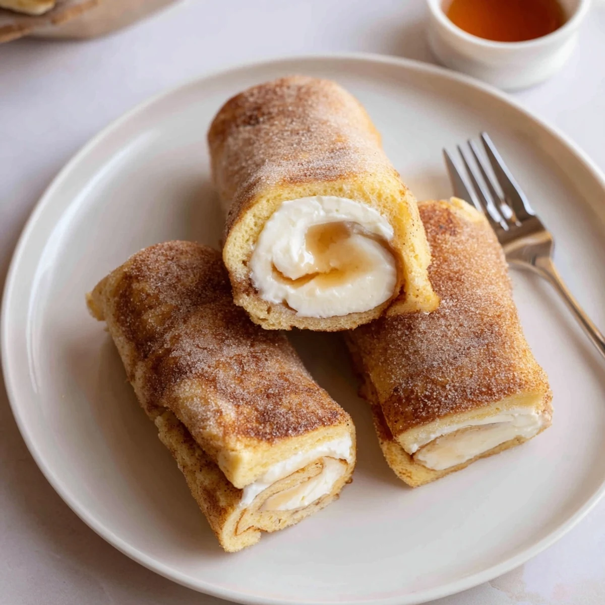 Skillet-fried Cinnamon Roll French Toast Roll Ups dusted in cinnamon sugar, steaming