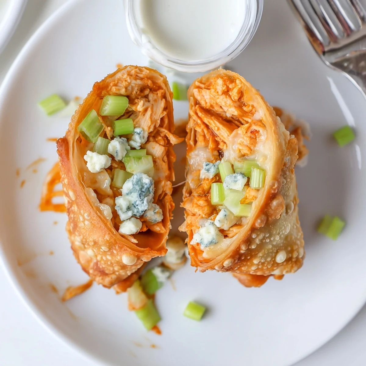 Golden-fried Buffalo Chicken Egg Rolls Recipe stacked on plate with ranch dip