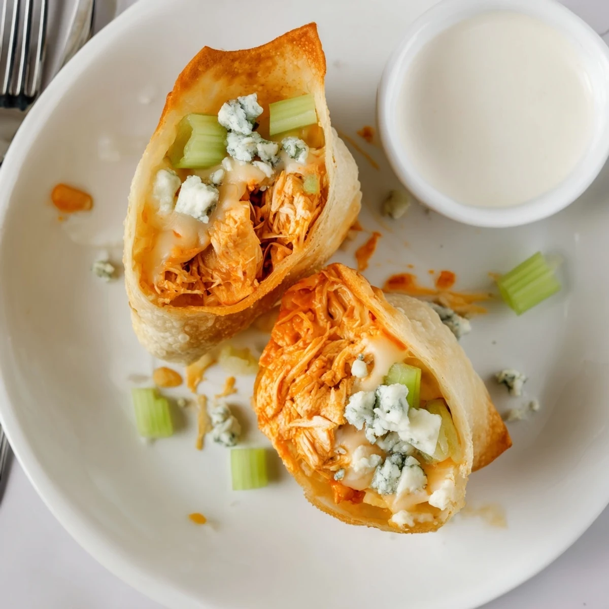 Crispy Buffalo Chicken Egg Rolls Recipe halved, melty cheese oozing, celery garnish