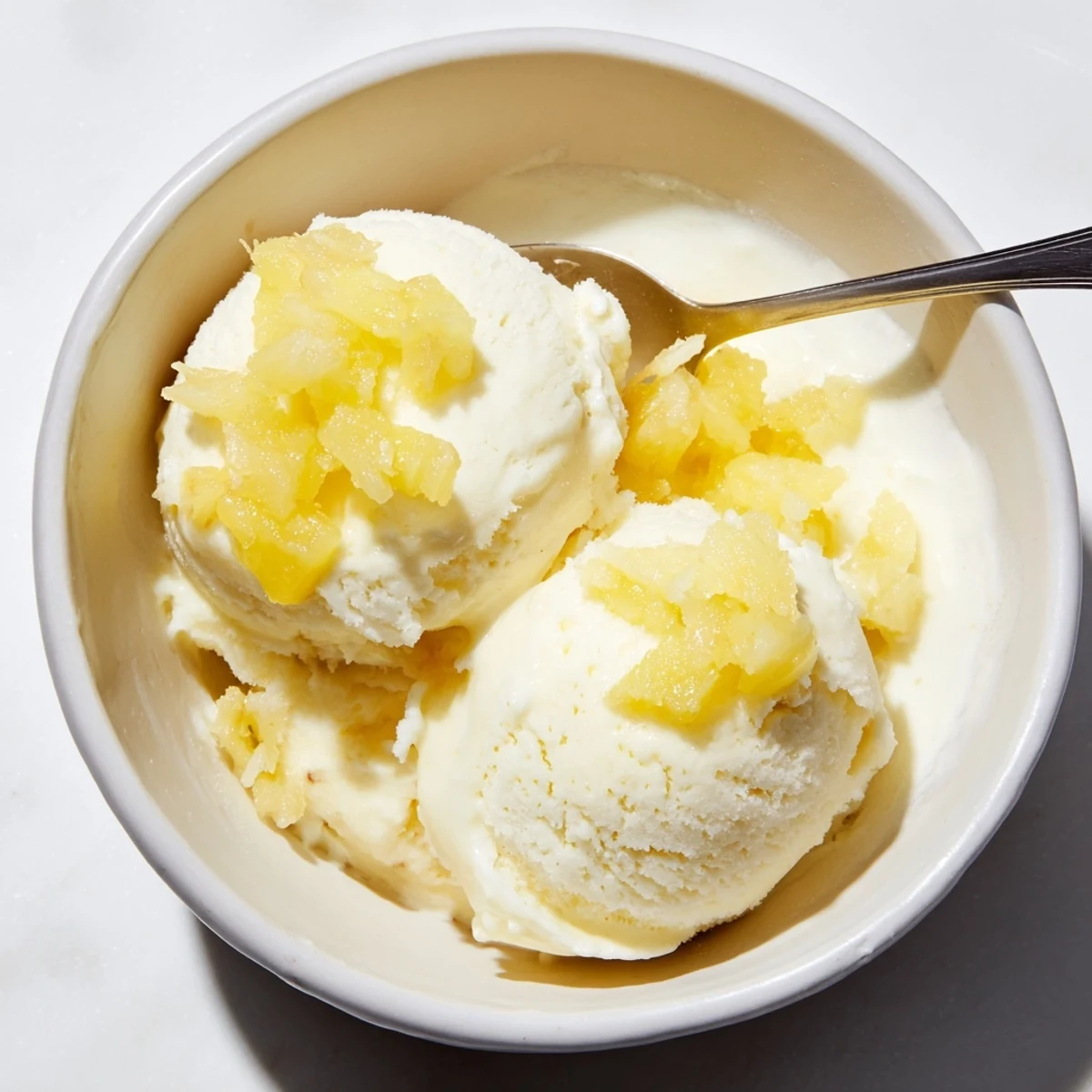A chilled bowl of Creamy Pineapple Ice Cream topped with toasted coconut.