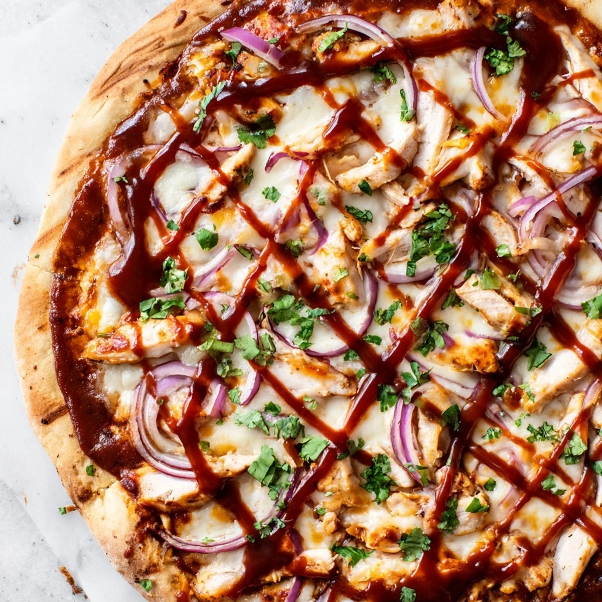 Homemade BBQ chicken pizza with grilled seasoned chicken, shredded gouda and mozzarella, sliced red onion, and chopped cilantro garnish.