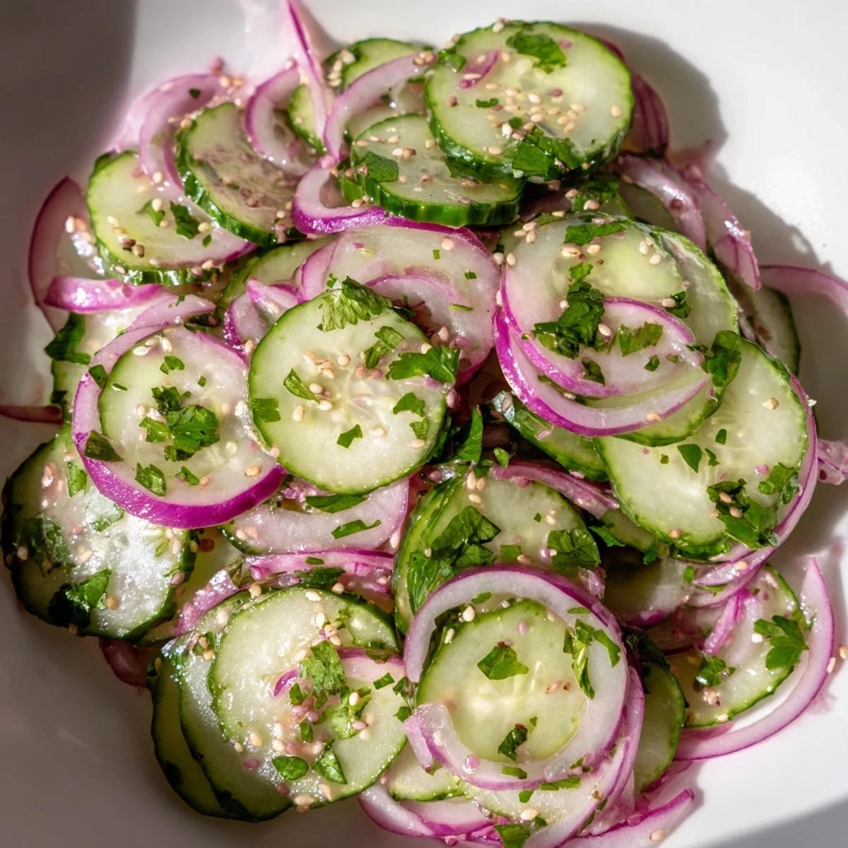 Fresh honey lime cucumber salad served in white bowl with vibrant cilantro garnish