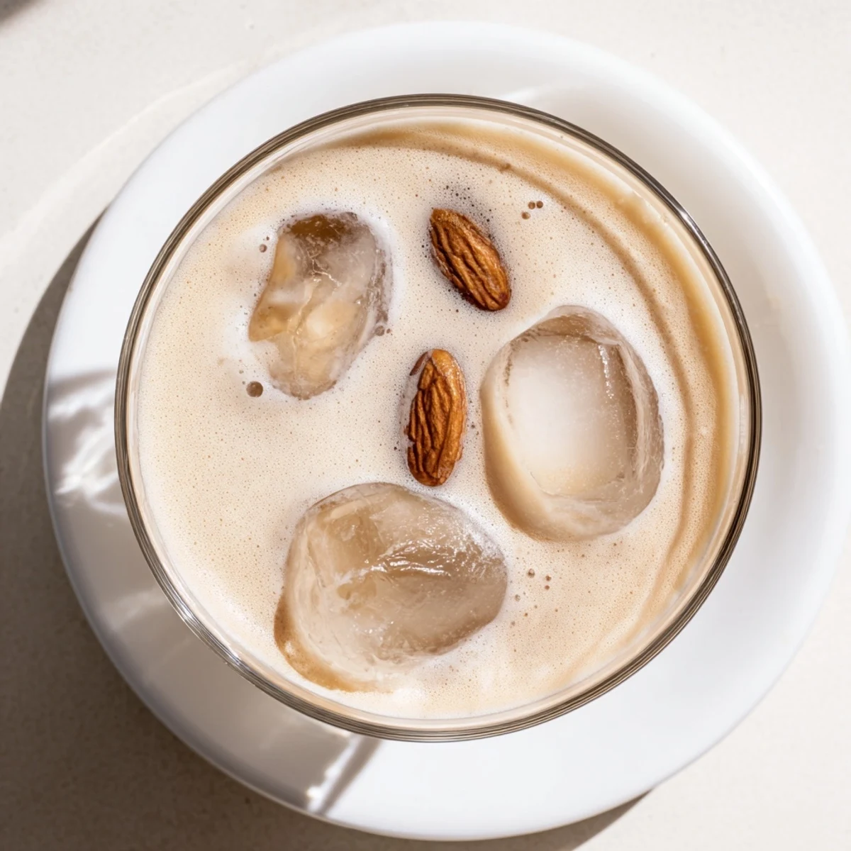 Light nutty roasted almond milk with cream garnish, a cooling summer drink in clear glassware