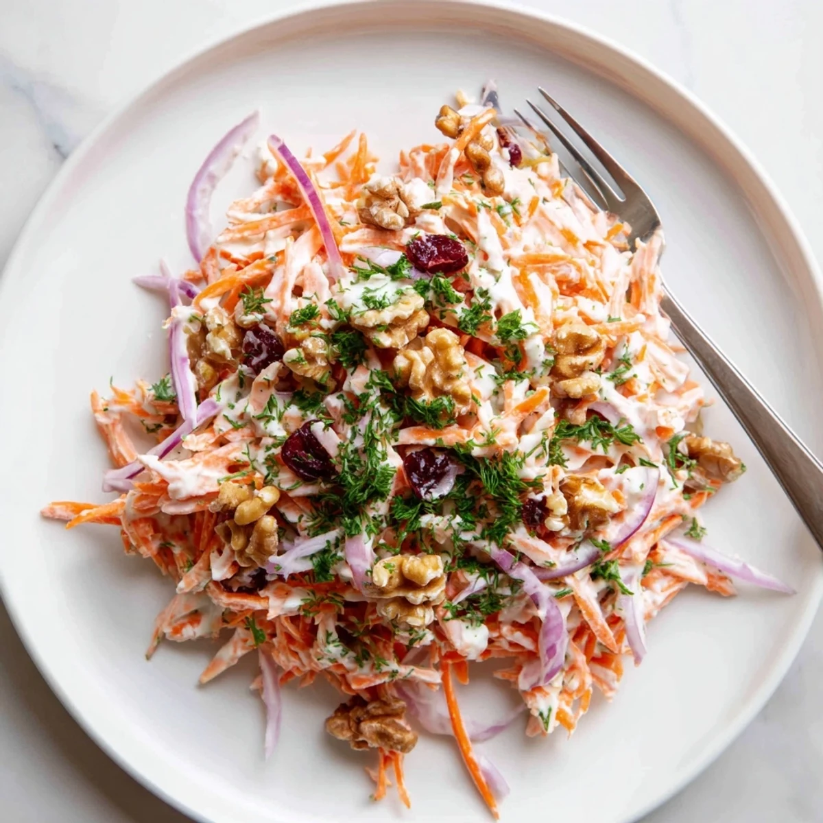 Vibrant apple carrot slaw topped with parsley and walnuts served chilled as a light side dish