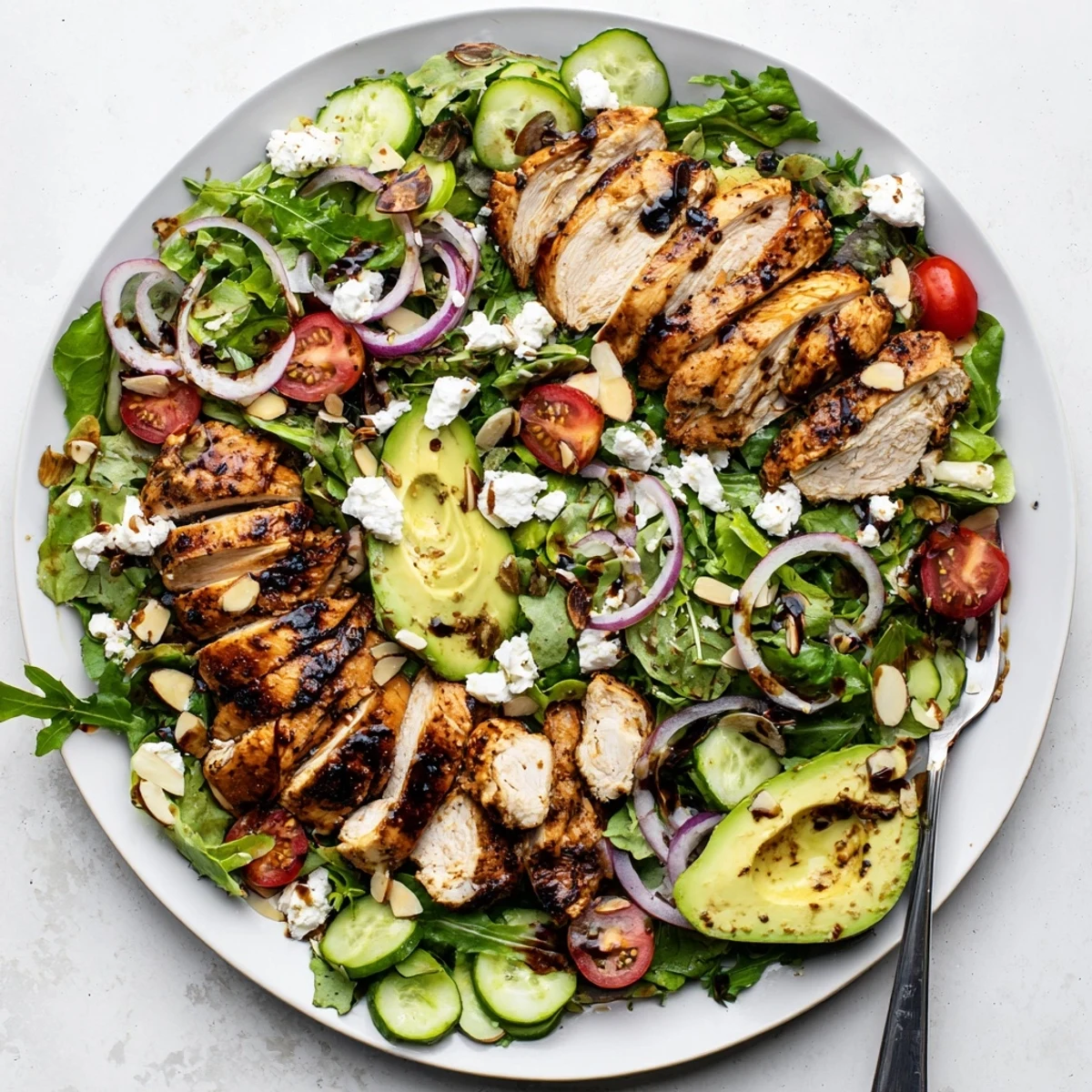 Golden grilled chicken slices atop mixed greens with colorful vegetables and tangy balsamic vinaigrette