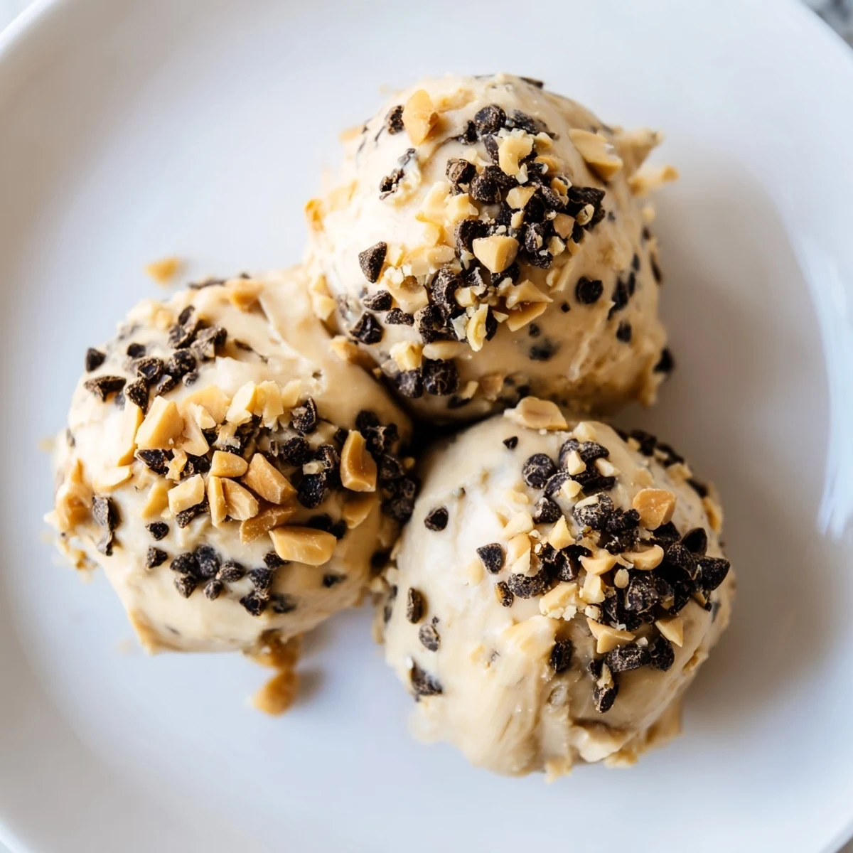 Creamy frozen peanut butter Greek yogurt bites topped with melted dark chocolate and crushed peanuts in a mini muffin tin