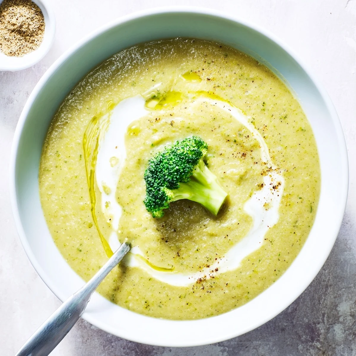 Broccoli Soup steaming in a bowl, cream swirl and toasted seeds