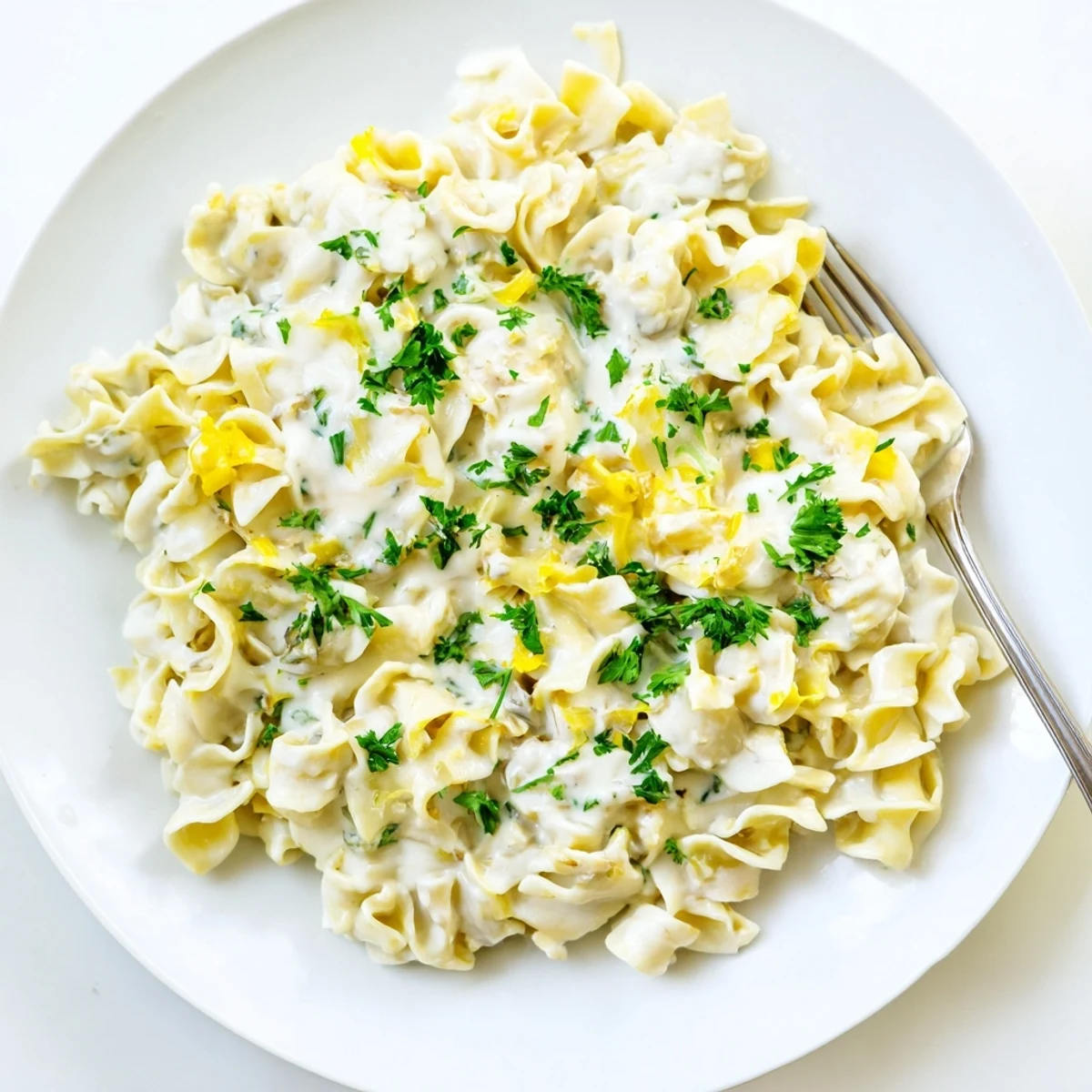Wide egg noodles swimming in savory white cheese sauce with a sprinkle of black pepper