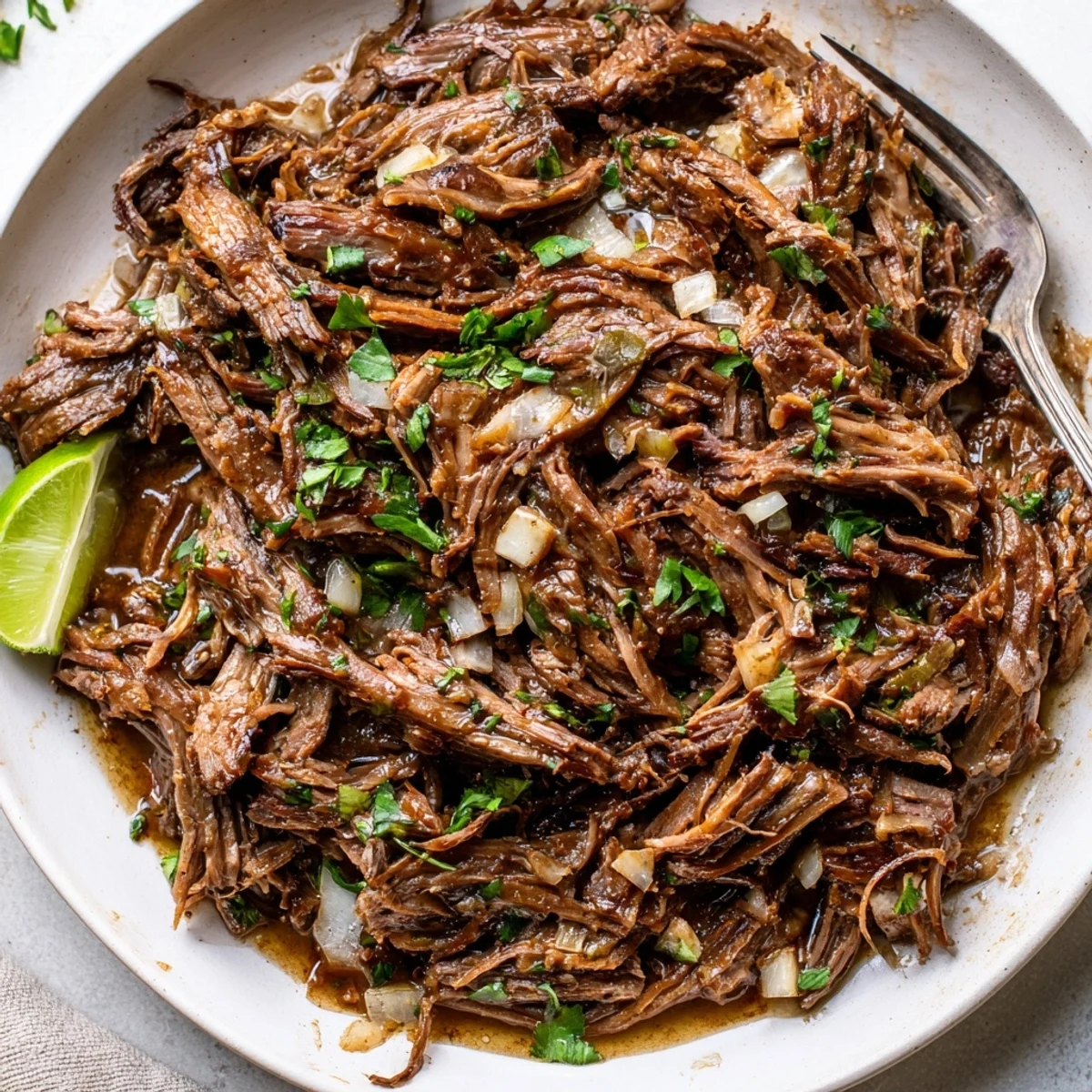 A bowl of Slow Cooker Beef Barbacoa glistening with juices, smoky aroma.