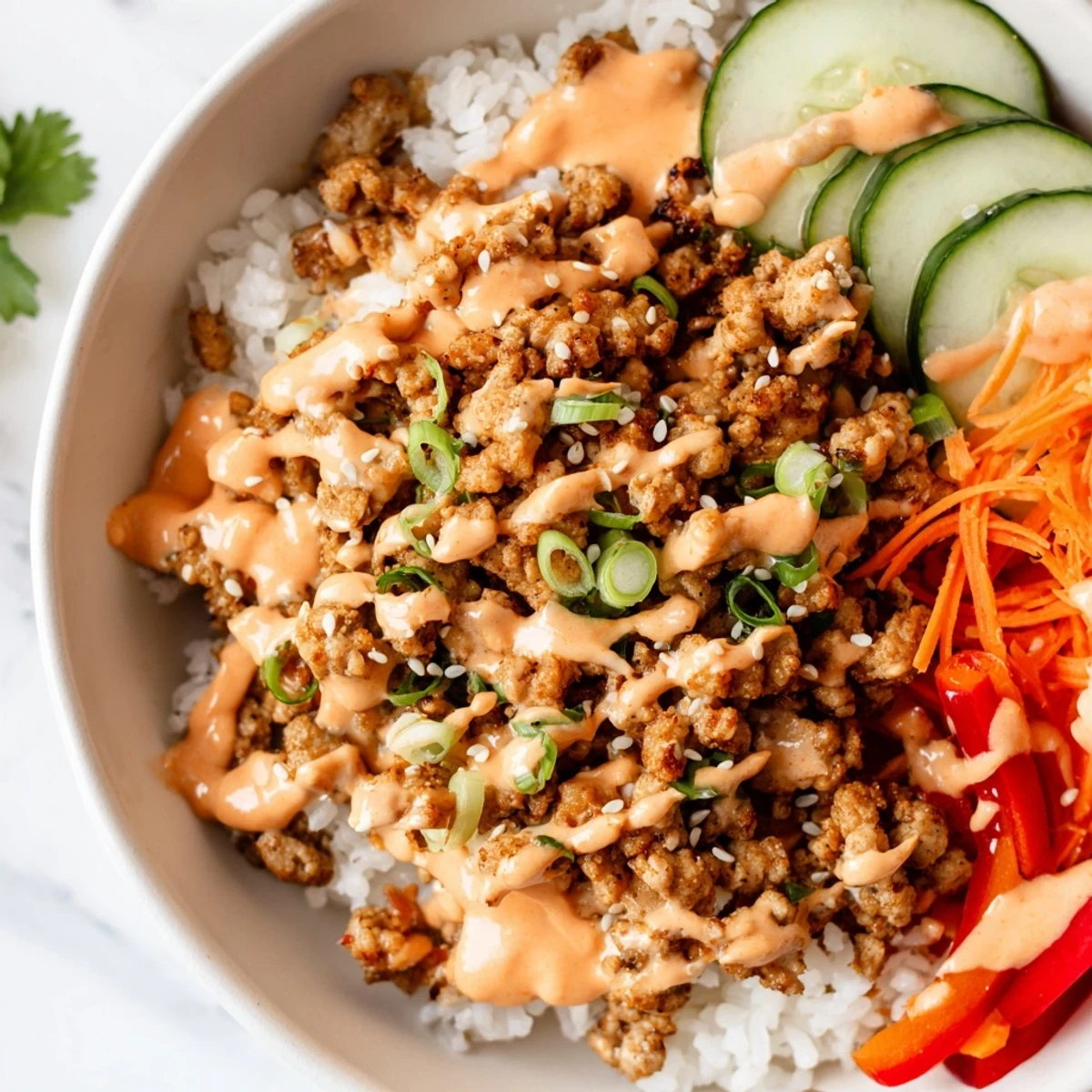 Golden seasoned ground turkey rice bowls topped with crunchy cucumber and spicy sauce.