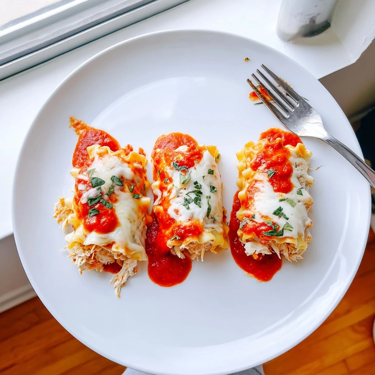 Creamy Garlic Parmesan Chicken Lasagna Roll Ups drizzled in rich white sauce over marinara
