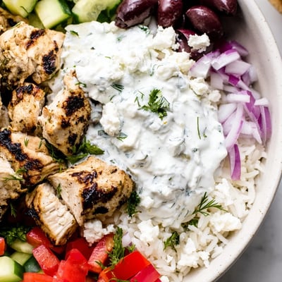 Colorful Greek chicken bowls featuring fluffy rice, crumbled feta, and vibrant Mediterranean toppings
